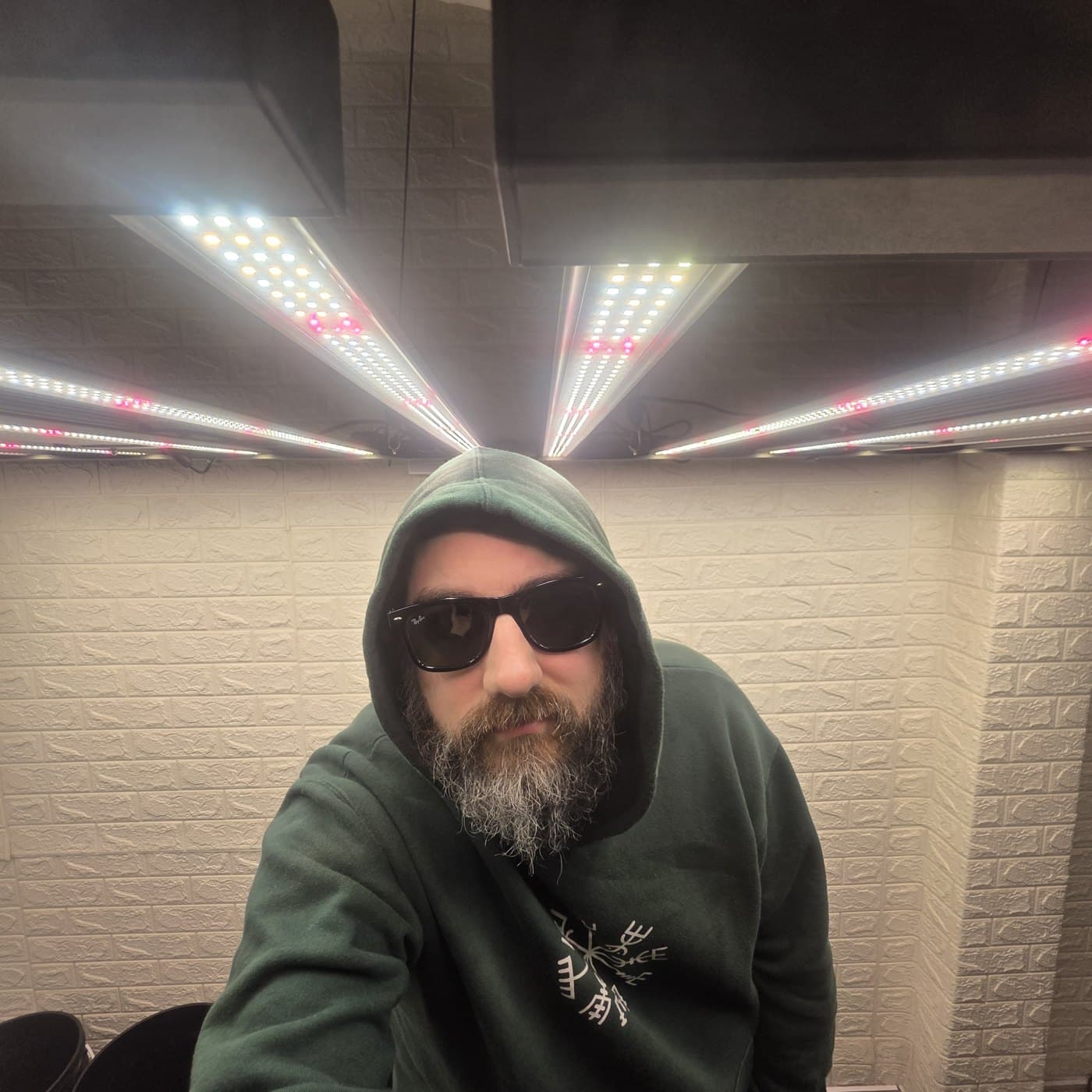 Iván con capucha y anteojos bajo las barras LED de su sala